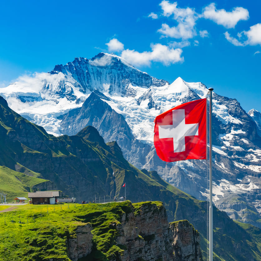 Schweizer Flagge weht vor schneebedeckten Bergen