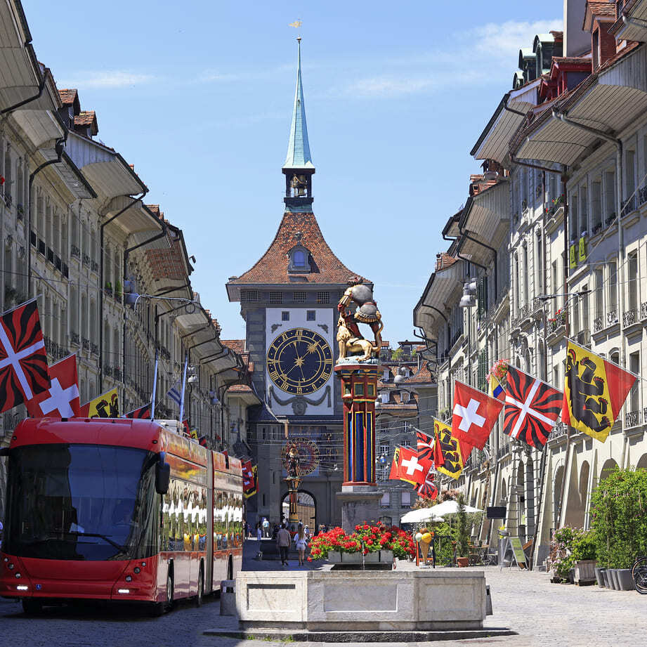 Straßenansicht in Bern mit Zytglogge und Schweizer Flaggen